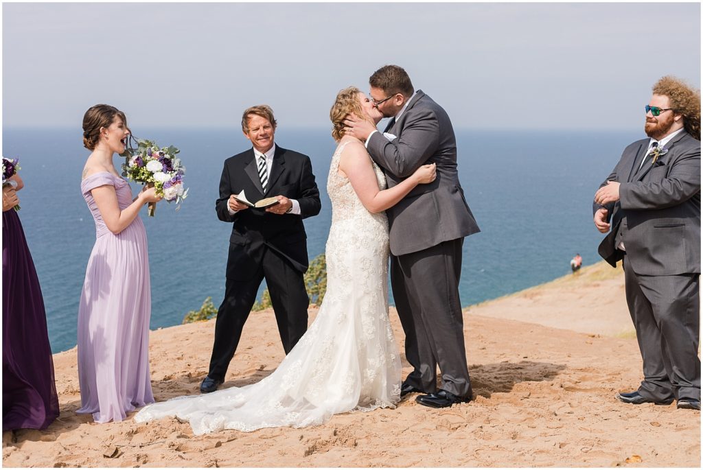 bride and groom sharing first kiss on sand dune