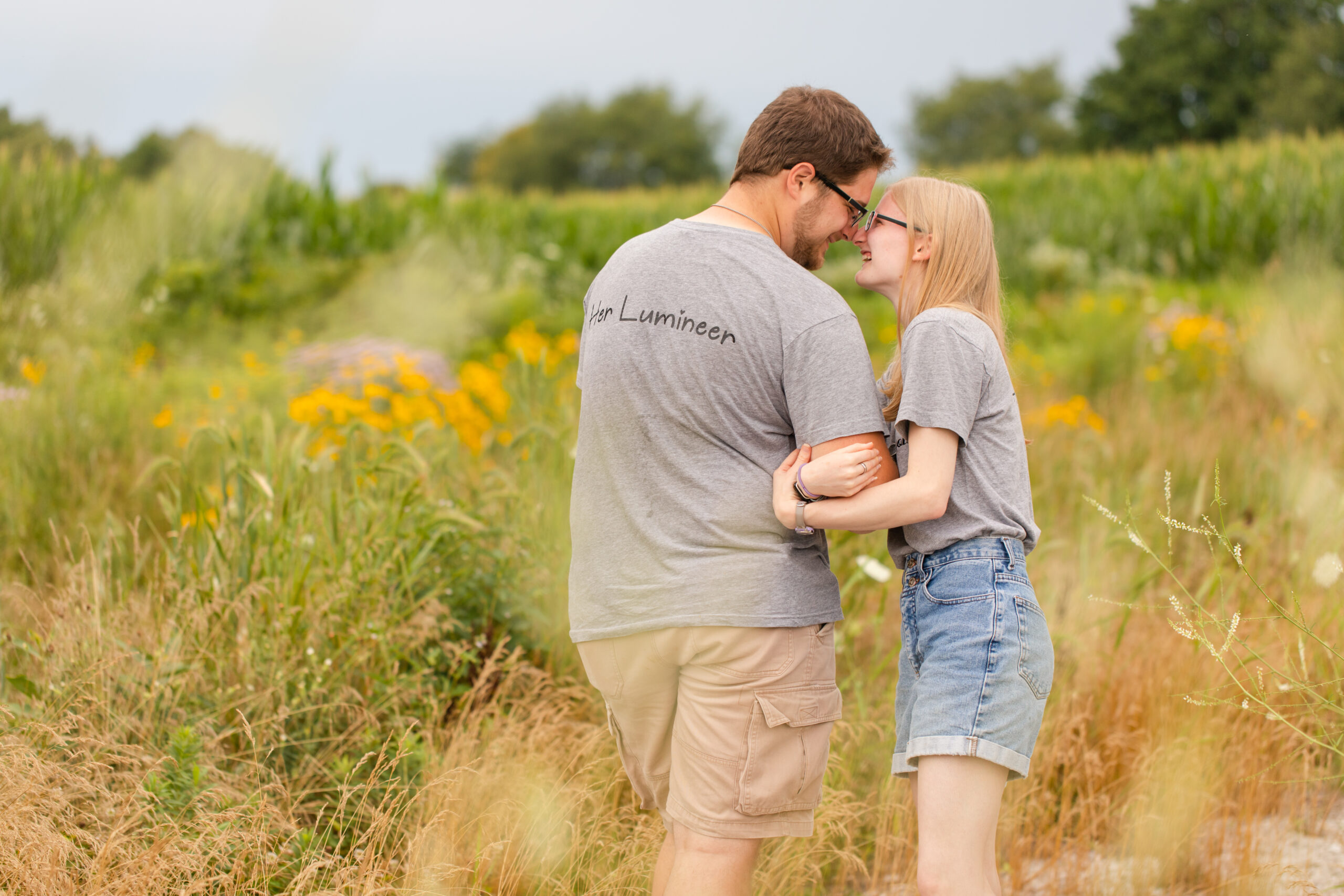 man and woman embracing face to face in a field of wildflowers
