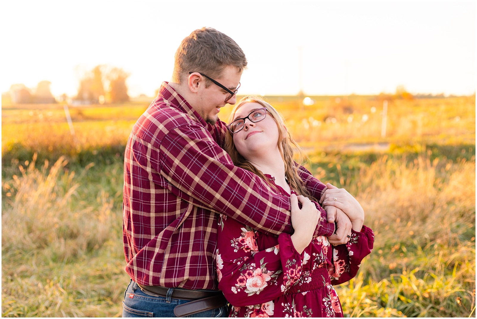 engaged couple in field during golden hour