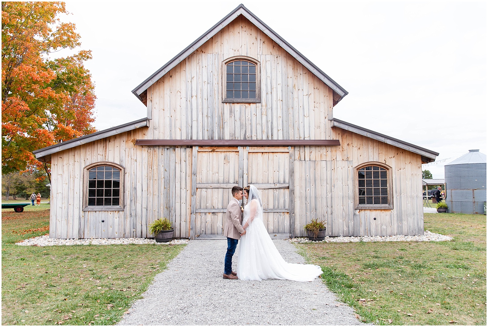 full view of a rustic barn with bride and groom embracing in front of it